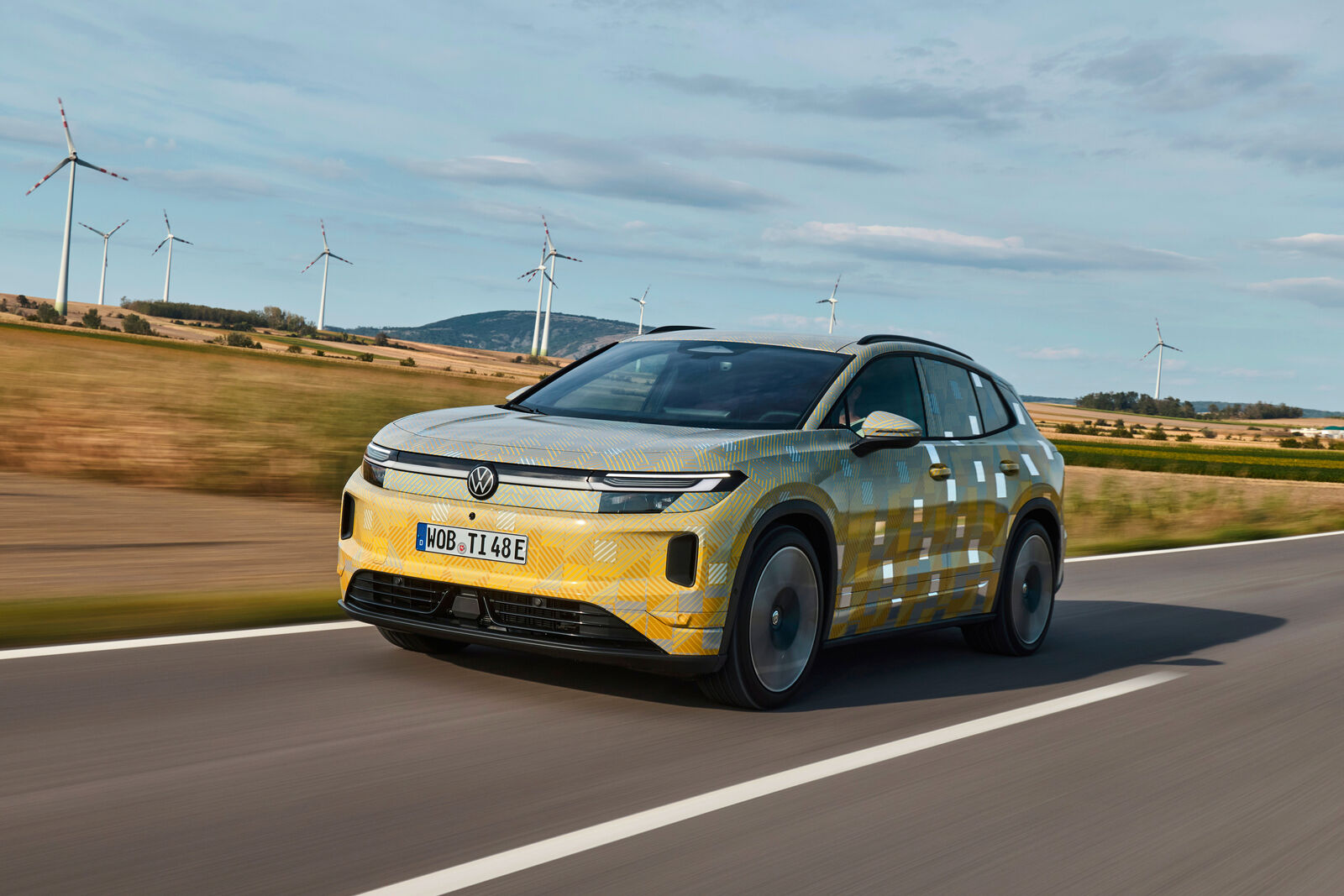 Predobočný pohľad na maskovaný prototyp Volkswagenu ID. Tiguan počas jazdy.