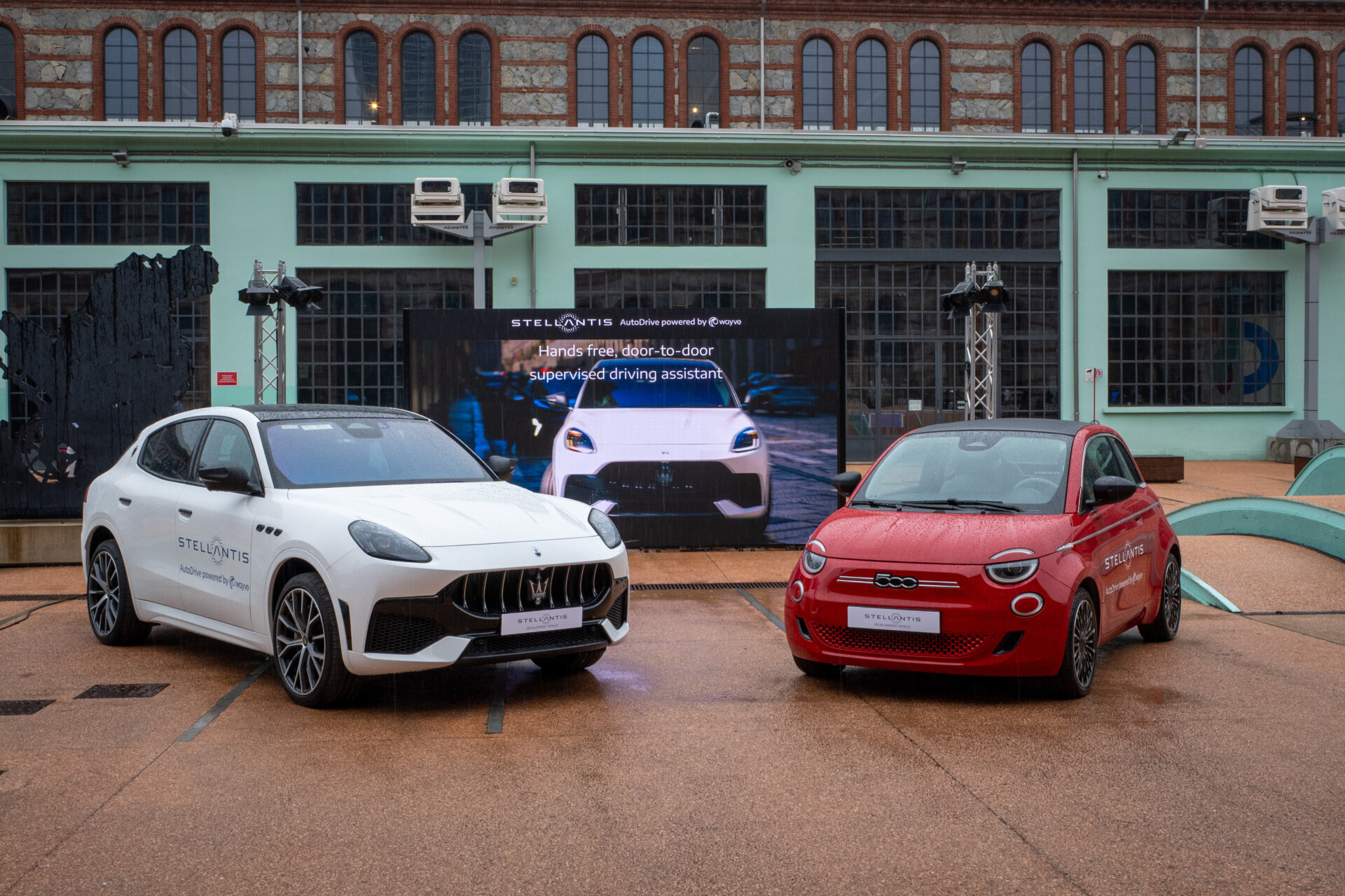 Červený elektrický Fiat 500e a biele Maserati Grecale pred budovou v Turíne.