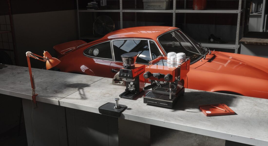 Kávovar a mlynček Porsche x La Marzocco pred oranžovou 911 Carrera RS 2.7