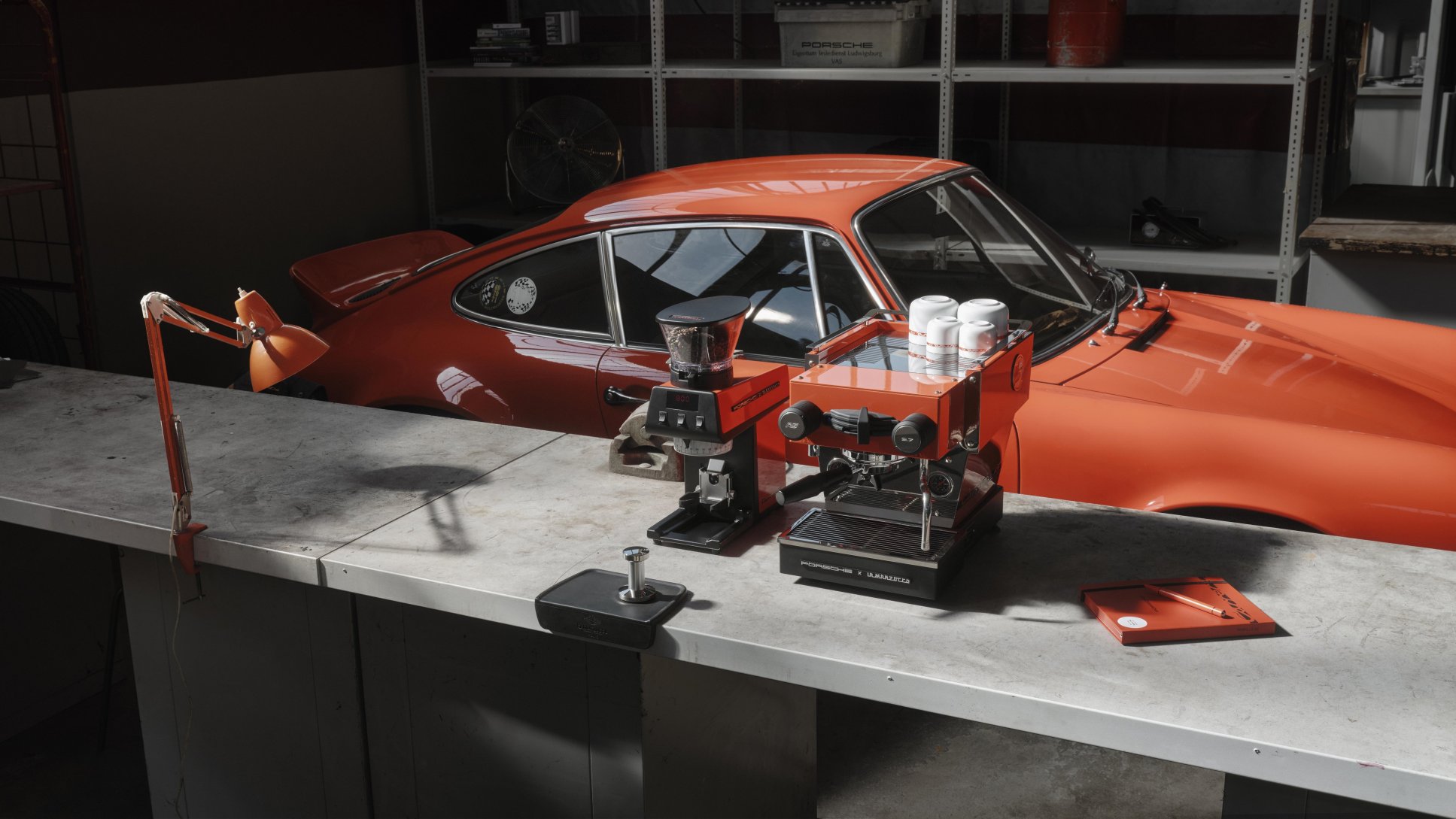 Kávovar a mlynček Porsche x La Marzocco pred oranžovou 911 Carrera RS 2.7